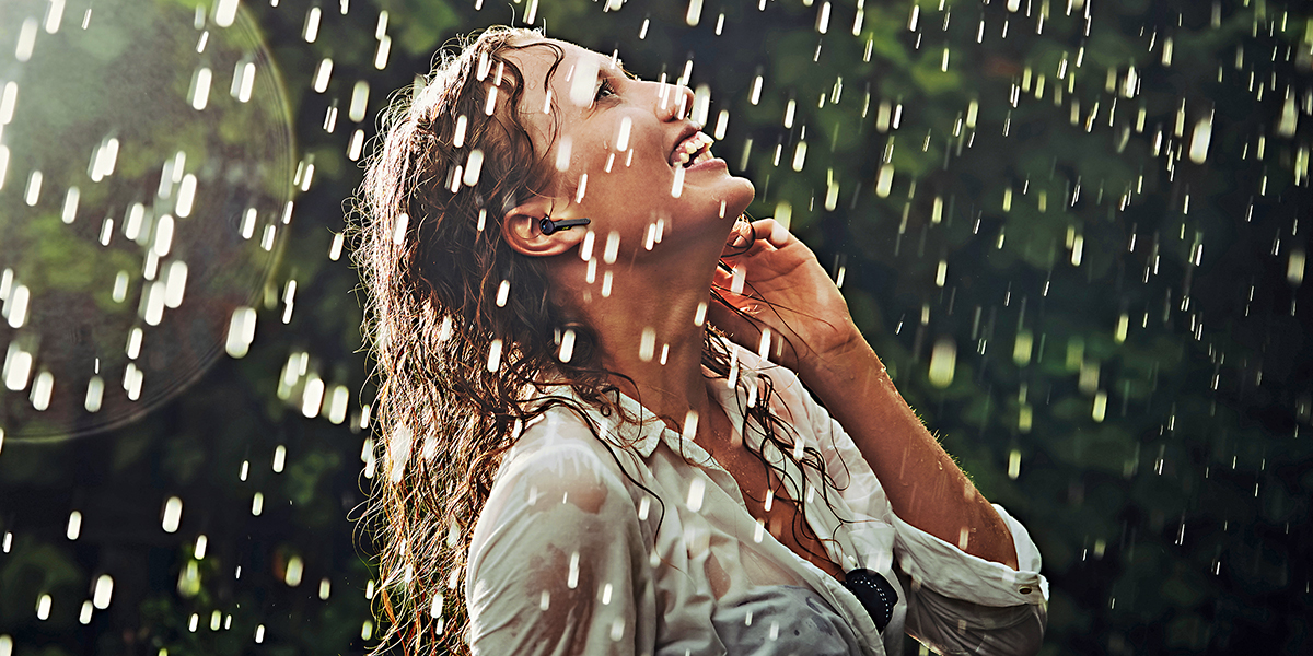 一位女士在雨中沒有撐傘，通過采用GORE?聲學透氣產品的耳機接聽電話。